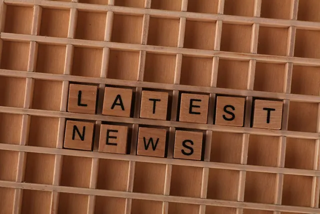 Wooden letter blocks spelling Latest News on a grid background, ideal for media themes.
