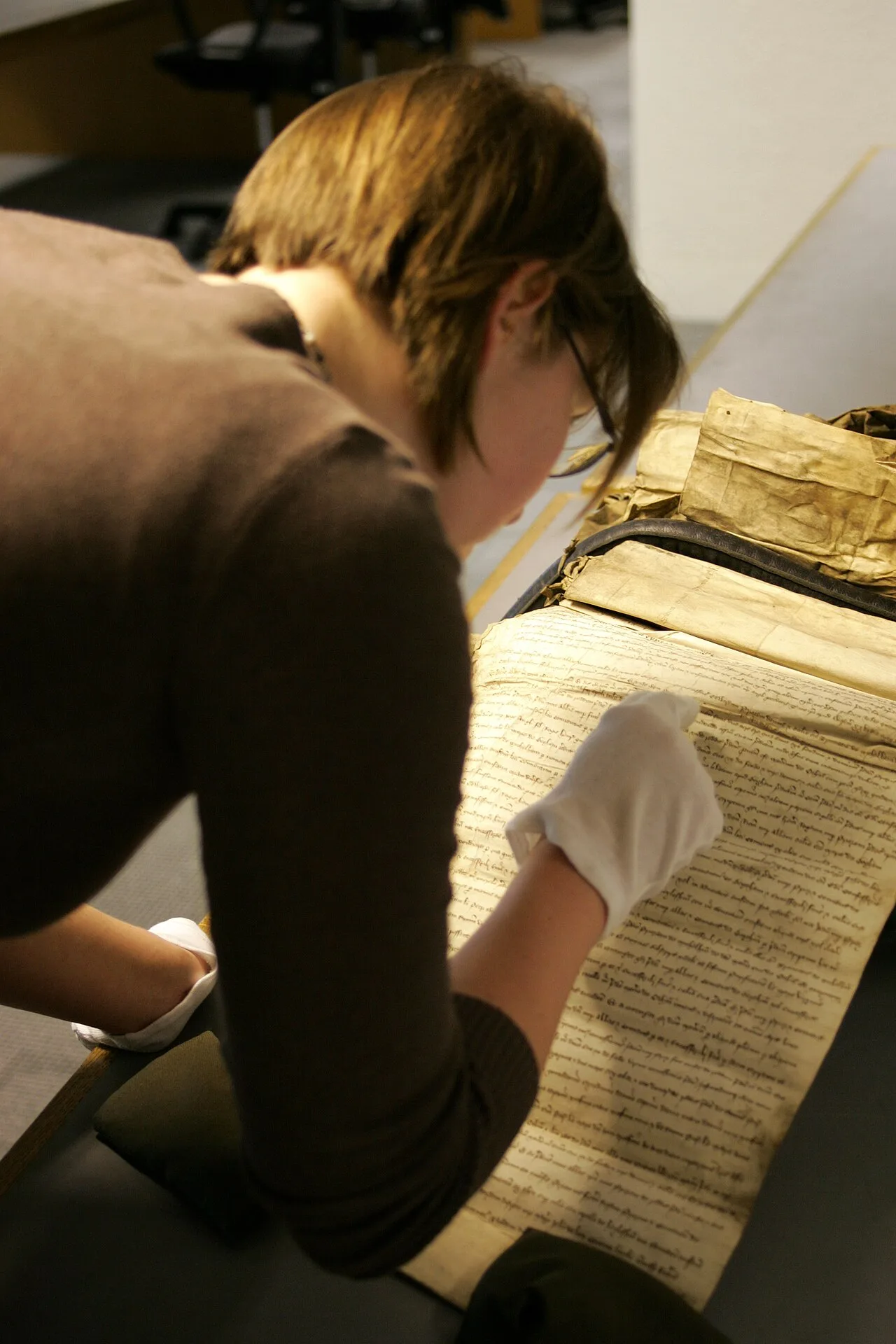 A researcher wearing gloves while examining a historical manuscript